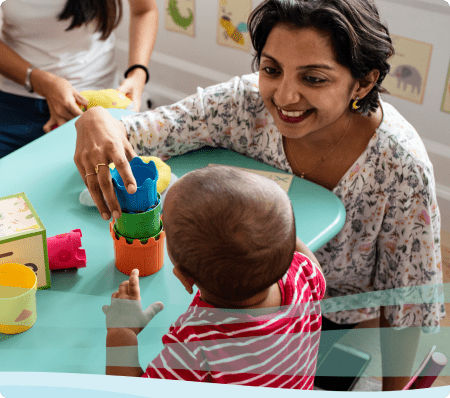 A teacher works with a small child by using colorful building blocks.