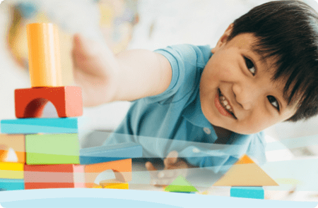 A child lies on the floor while playing with colorful blocks.