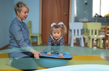 A childcare administrator uses a bosu ball to work with a child on balance.